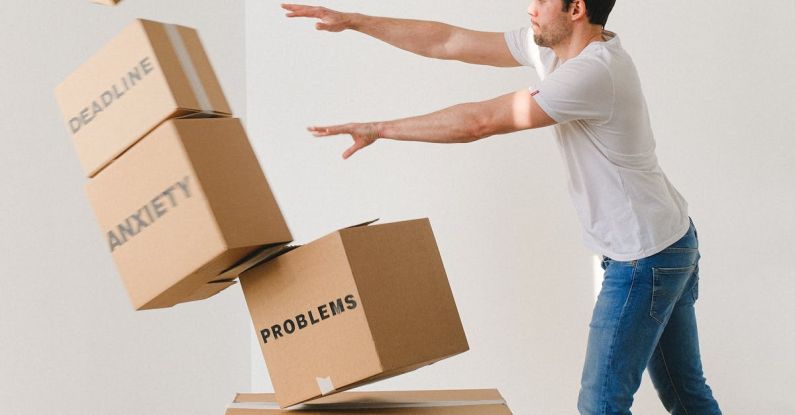 Manage Change - Full body of young man in sneakers and jeans pushing and falling boxes saying Work Problems Anxiety Stress and Deadline while fighting with problems